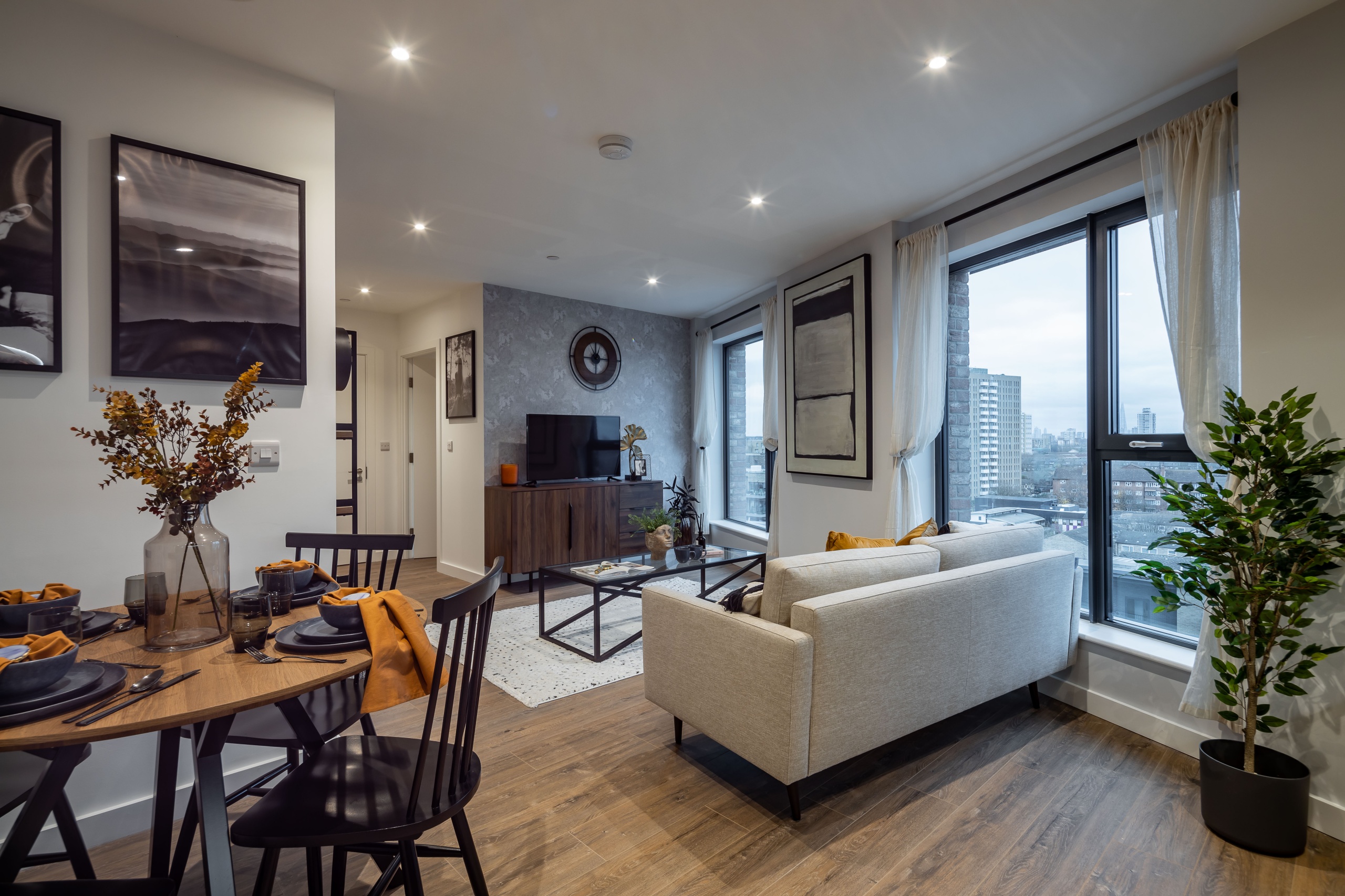 Living area of an apartment with large windows giving views of the city