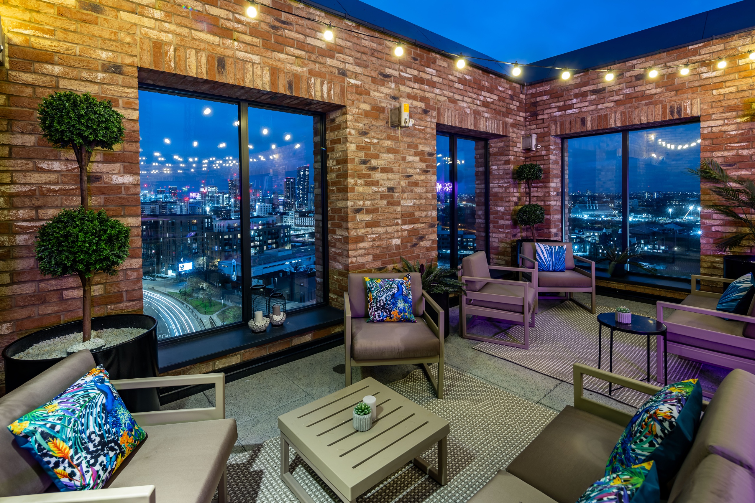 Rooftop terrace with lots of seats and plants that has a view of the city