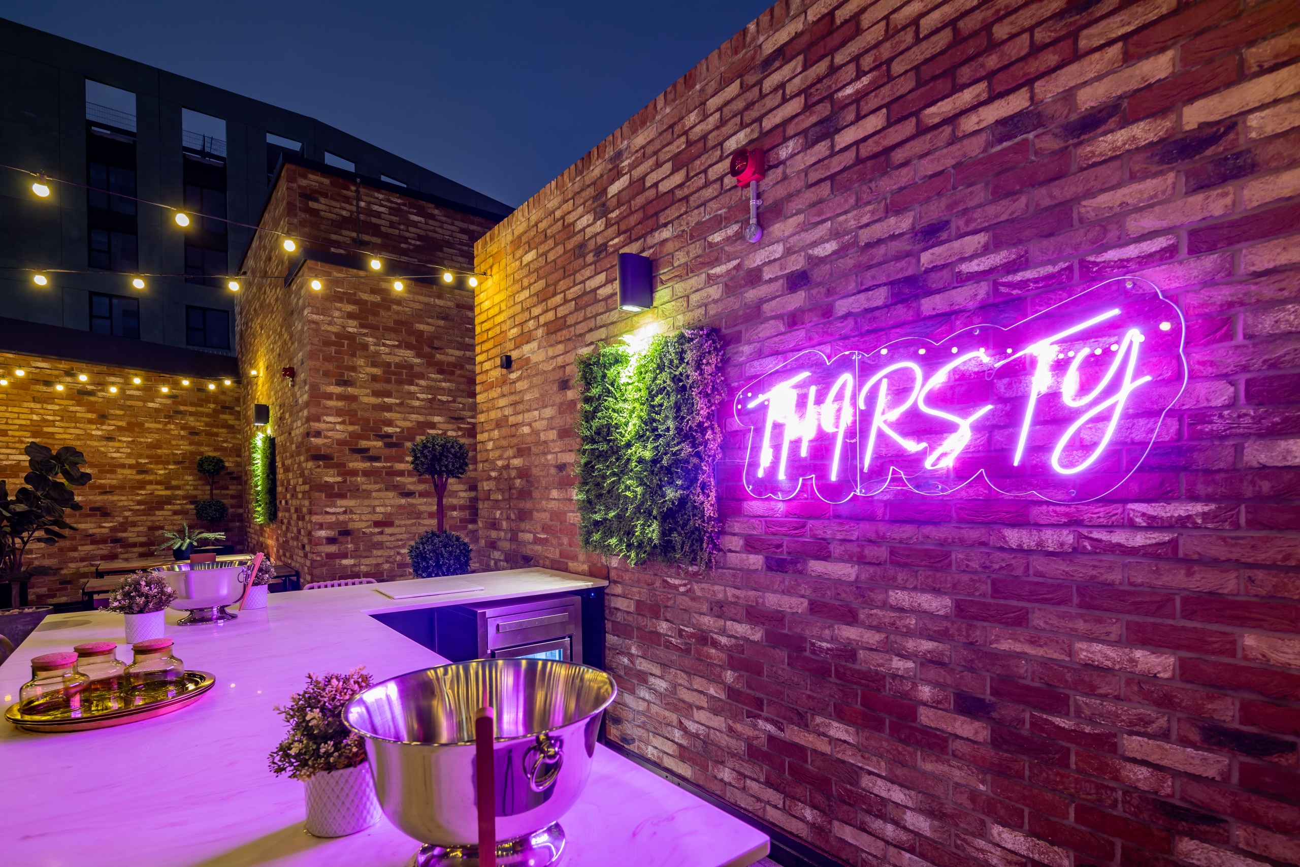 Large brick wall behind a kitchen countertop with a purple illuminated sign