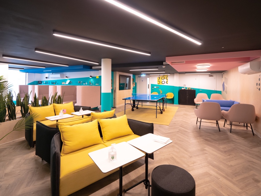 Bright communal area with a ping pong table in the middle and lots of chairs and sofas