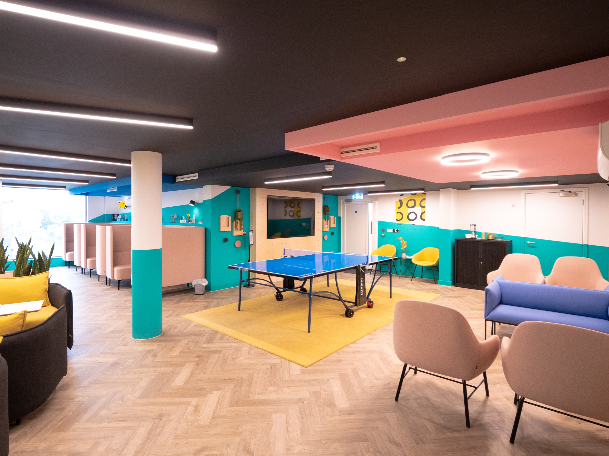 Bright communal area with a ping pong table in the middle and lots of chairs and sofas