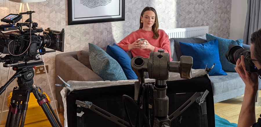 women sat on the sofa with a hot drink being filmed by a camera crew