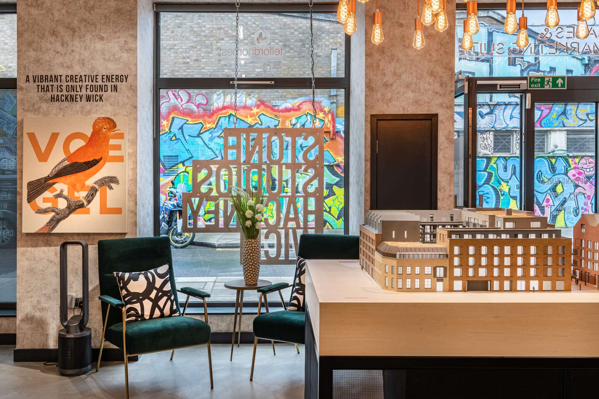 Room with large windows and a table in the middle that has a 3D model of a building on it