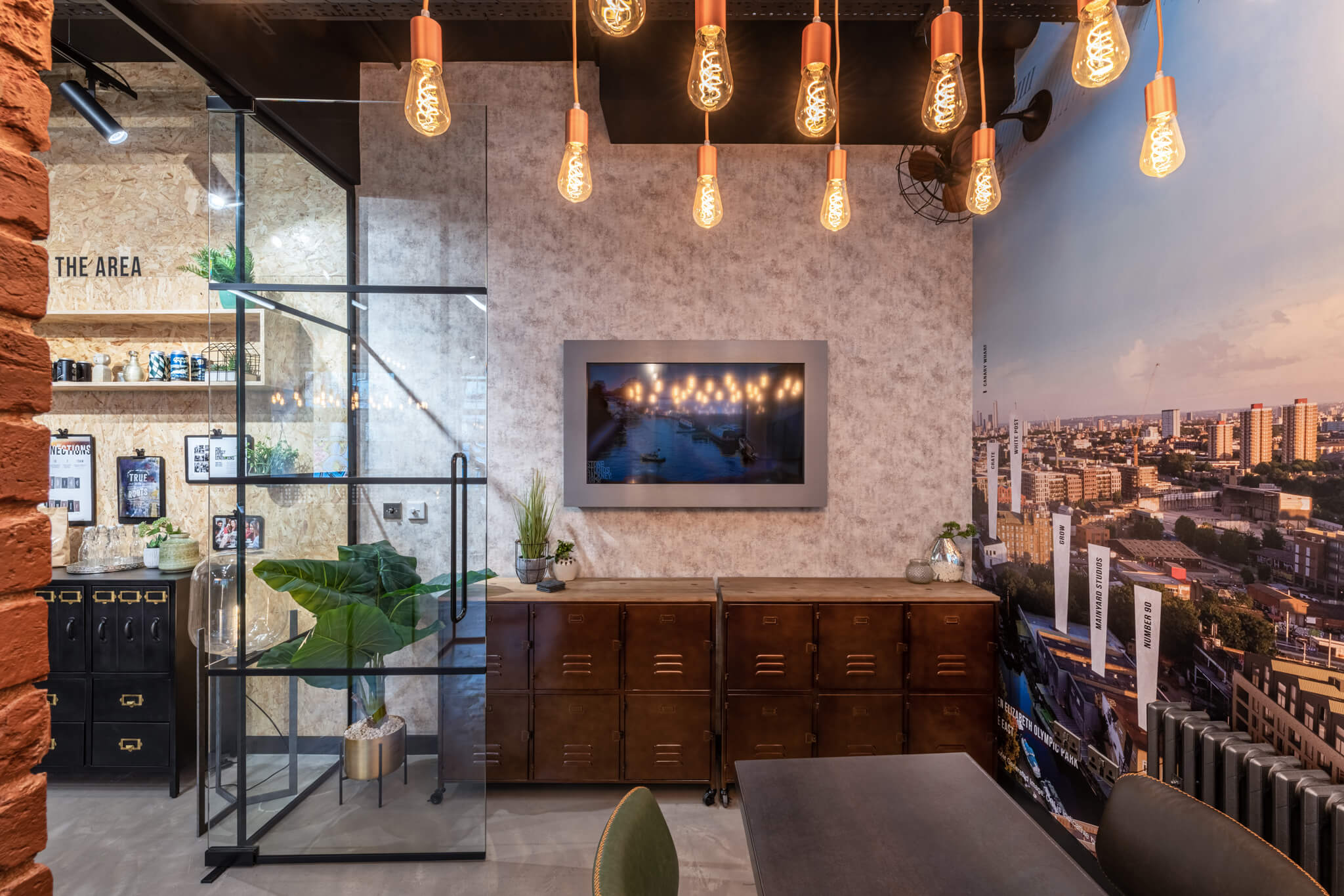 TV mounted to a wall below multiple lamps that are attached to the ceiling