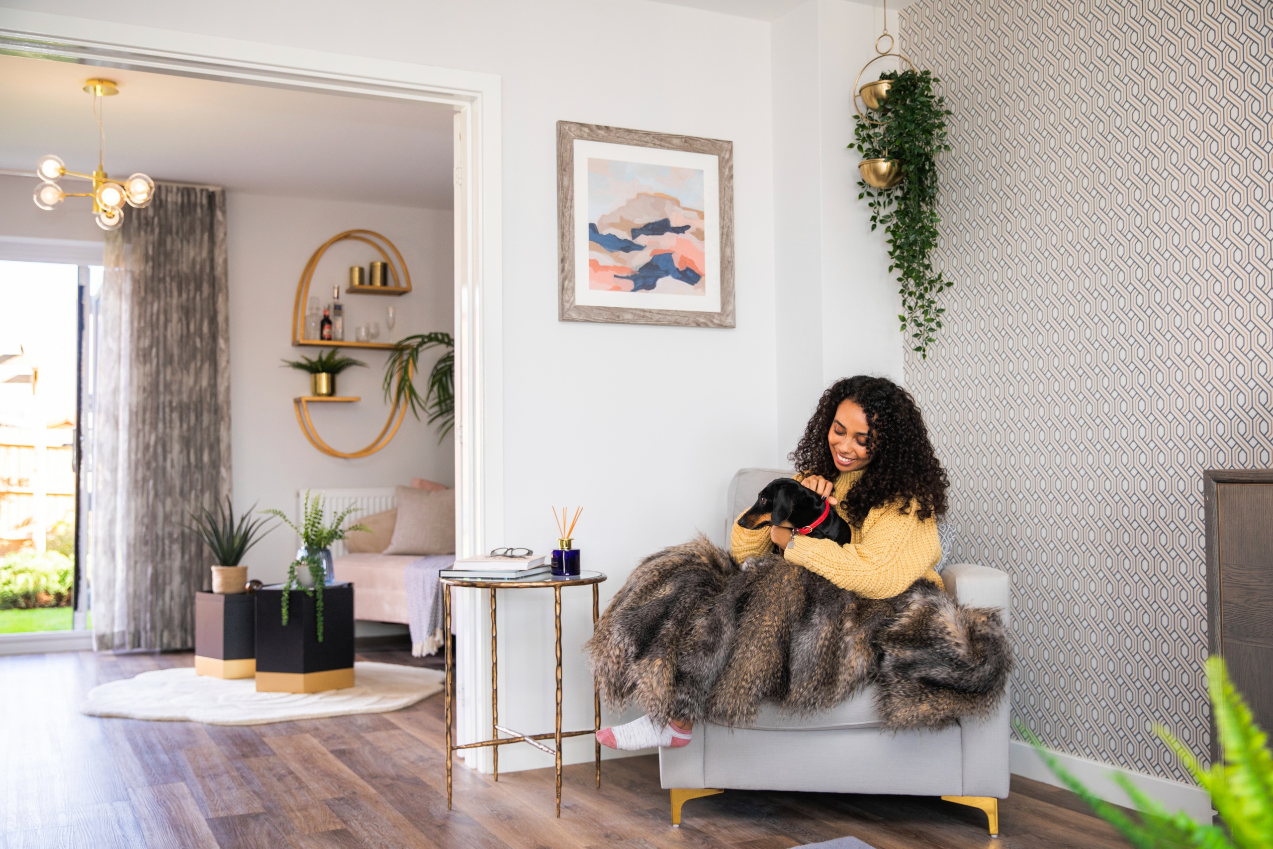 A women sat on an armchair in her modern living room cuddling her dog