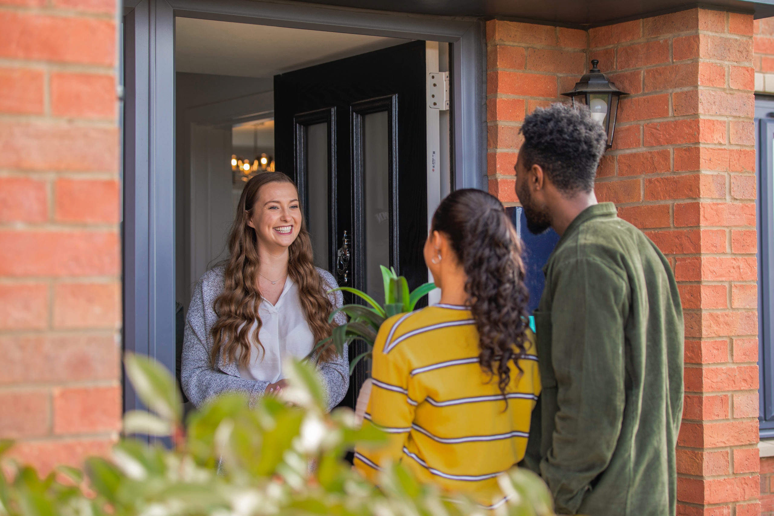 A couple visiting their friend at her home and gifting her a plant