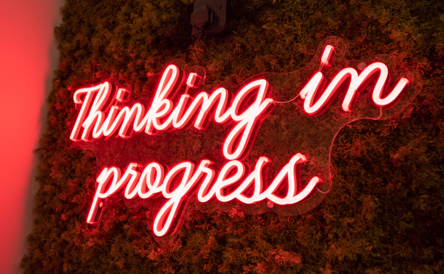 Red illuminated sign on a backdrop of artificial plants