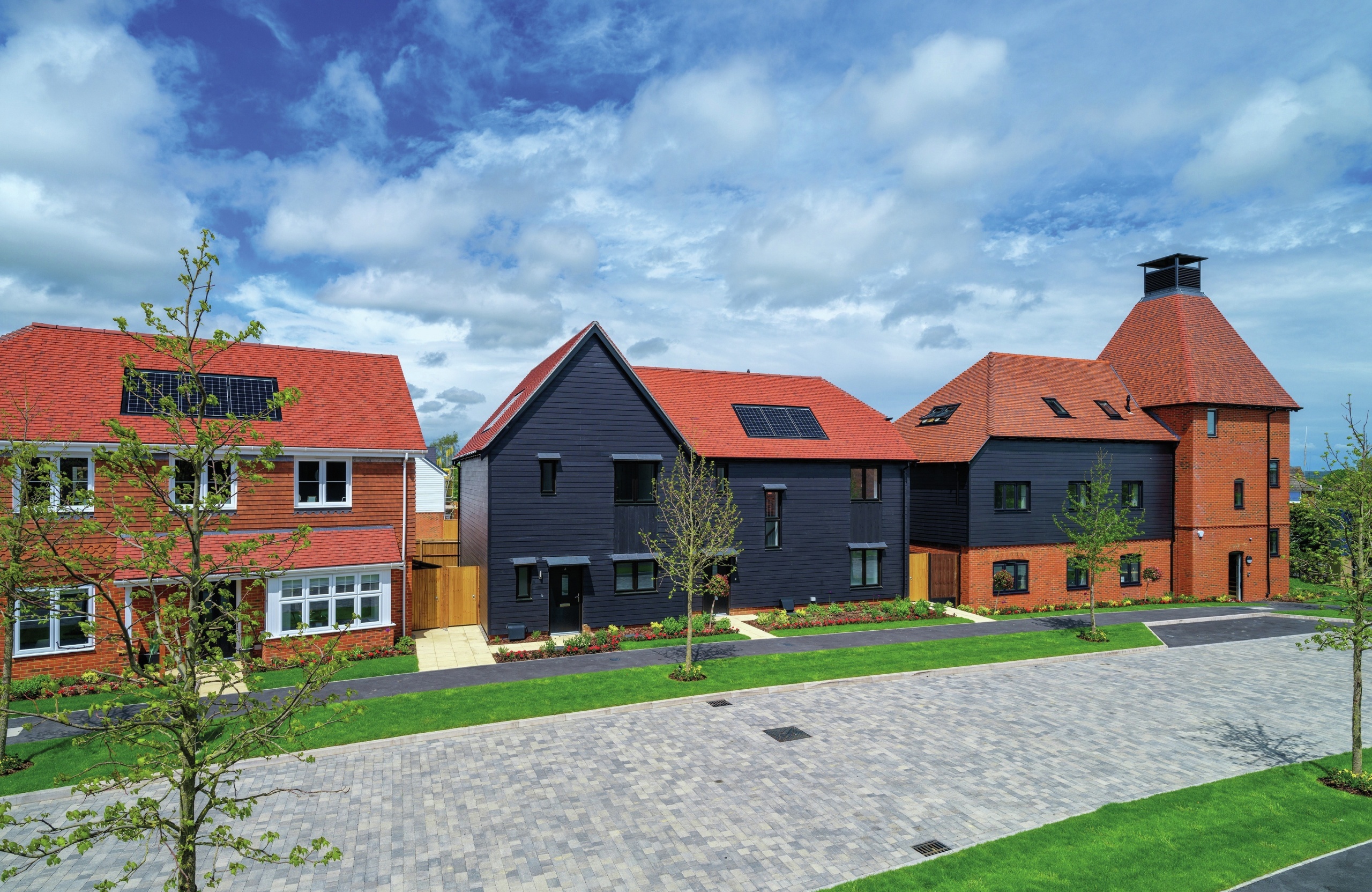 A street with modern houses, lots of green space and trees.