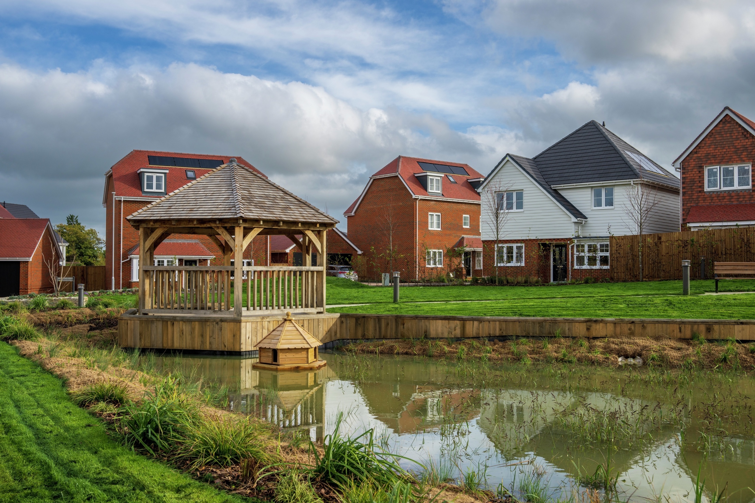 A modern housing estate with several houses and a community pond in the centre